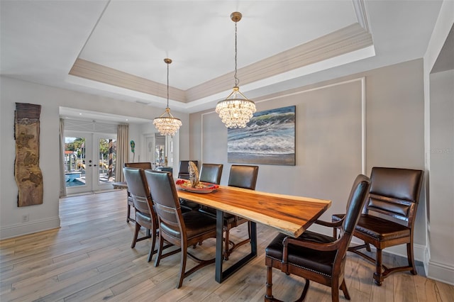 dining area featuring a tray ceiling, french doors, and light hardwood / wood-style floors