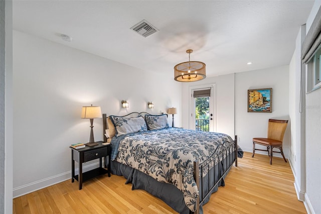 bedroom with light hardwood / wood-style flooring and an inviting chandelier