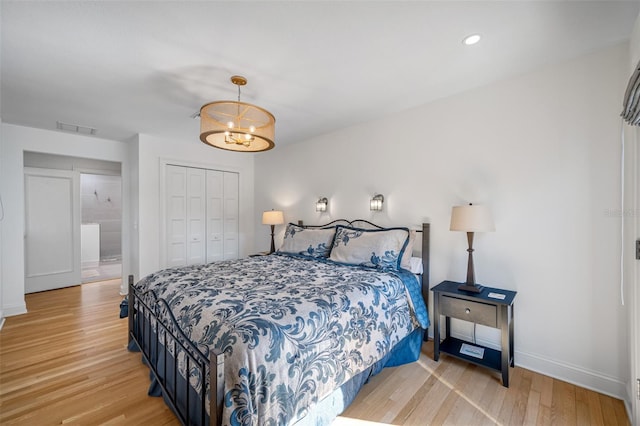 bedroom featuring a closet, light hardwood / wood-style flooring, and an inviting chandelier