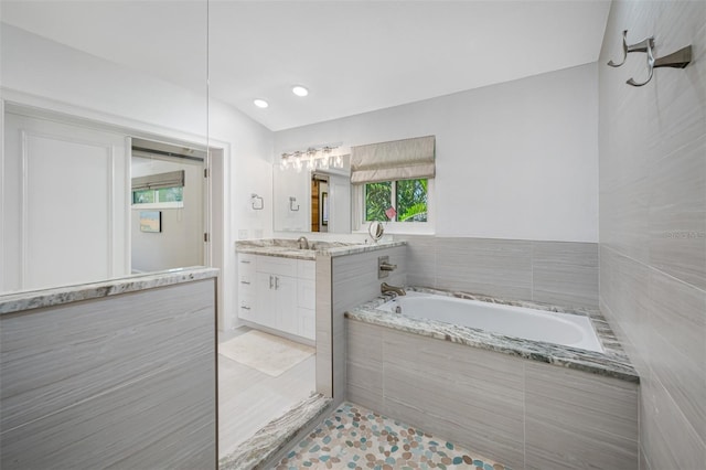 bathroom with tile patterned floors, vanity, and tiled bath