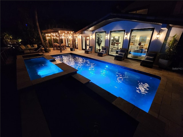 pool at twilight featuring an in ground hot tub and a patio area