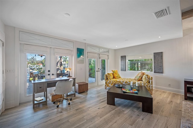 living room featuring plenty of natural light, light hardwood / wood-style floors, and french doors