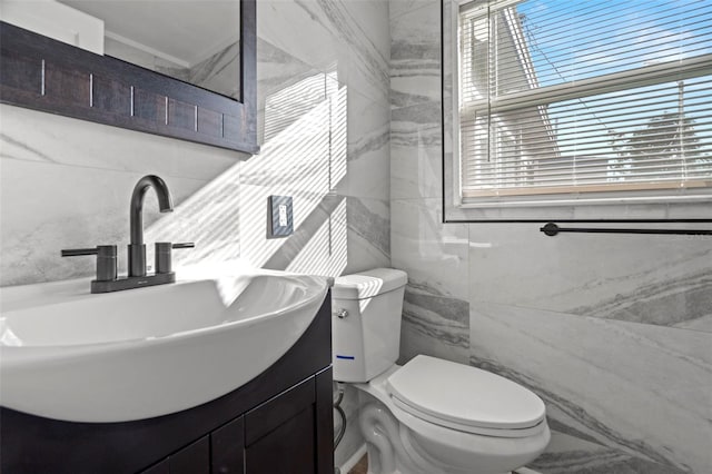 bathroom featuring vanity, toilet, and tile walls