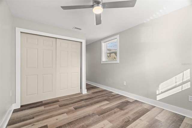 unfurnished bedroom with dark hardwood / wood-style floors, ceiling fan, and a closet