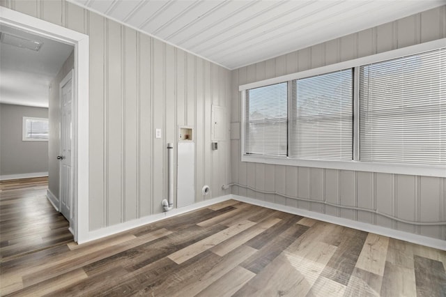 spare room with wood walls, plenty of natural light, and hardwood / wood-style flooring