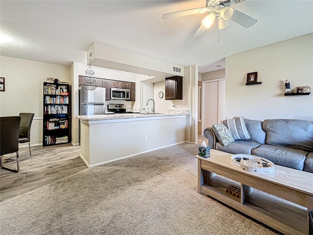 carpeted living room with ceiling fan and sink