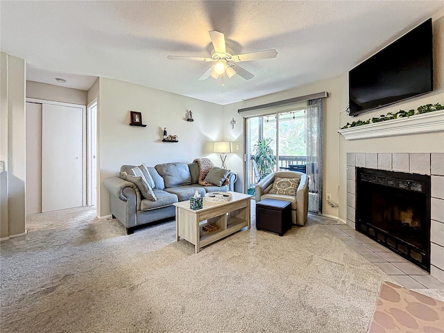 living room featuring light carpet, ceiling fan, a tiled fireplace, and a textured ceiling