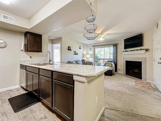 kitchen with a tile fireplace, sink, kitchen peninsula, dark brown cabinets, and a textured ceiling