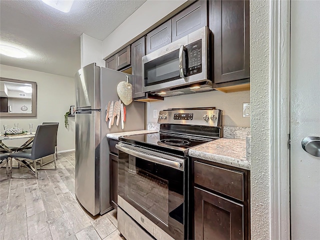 kitchen featuring stainless steel appliances, dark brown cabinets, and a textured ceiling