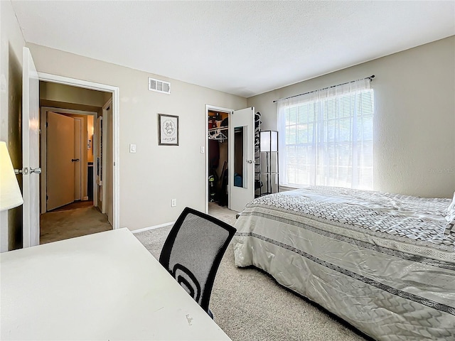 carpeted bedroom with a walk in closet, a textured ceiling, and a closet