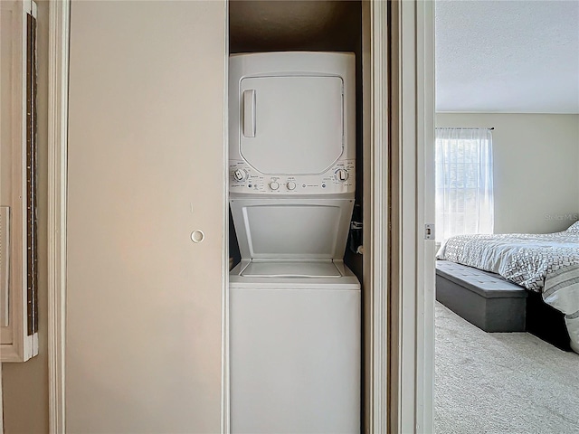 laundry room with stacked washer and dryer, carpet flooring, and a textured ceiling