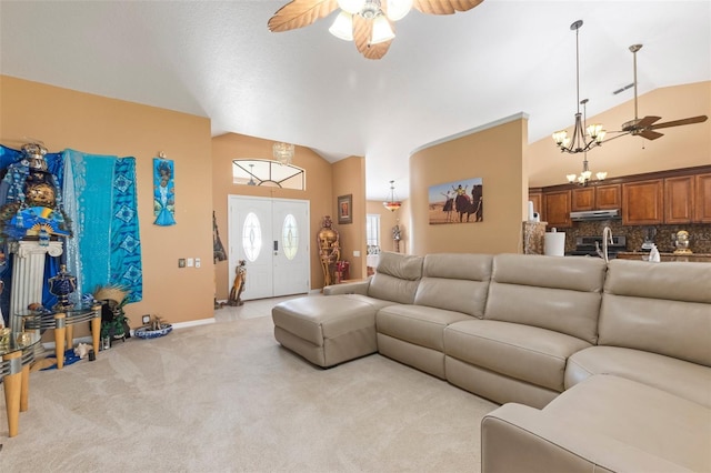 carpeted living room with ceiling fan with notable chandelier and high vaulted ceiling