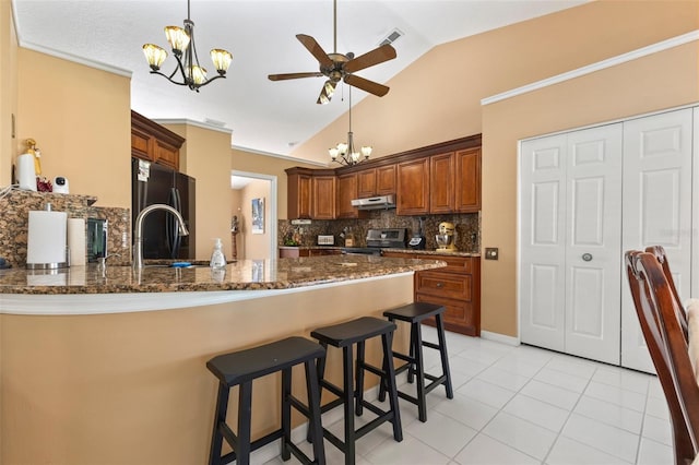 kitchen featuring kitchen peninsula, black fridge, dark stone countertops, stainless steel range oven, and lofted ceiling