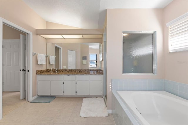 bathroom featuring vanity, tile patterned floors, vaulted ceiling, a relaxing tiled tub, and a textured ceiling