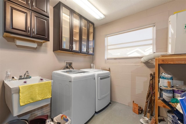 clothes washing area featuring a textured ceiling, cabinets, separate washer and dryer, and sink