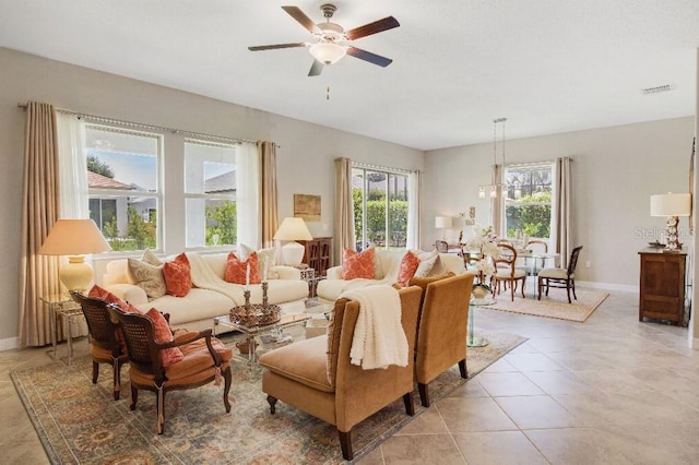 tiled living room with ceiling fan with notable chandelier