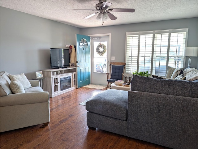 living room with ceiling fan, dark hardwood / wood-style flooring, and a textured ceiling