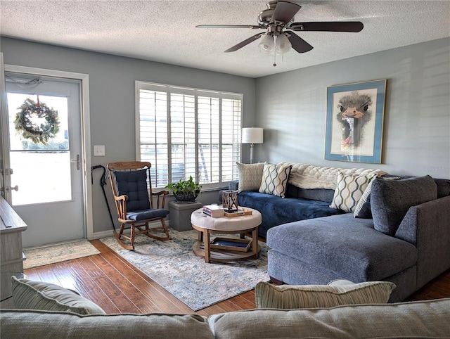 living room with ceiling fan, dark wood-type flooring, and a textured ceiling