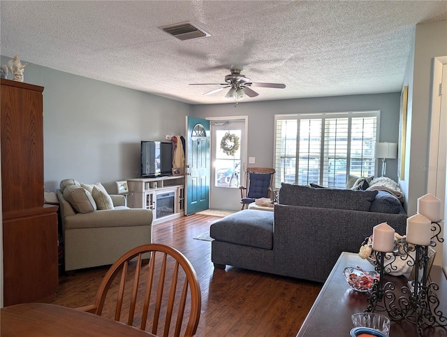 living room with dark hardwood / wood-style floors, a textured ceiling, and ceiling fan