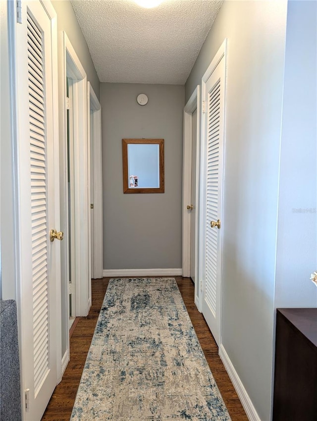 hallway with dark hardwood / wood-style floors and a textured ceiling