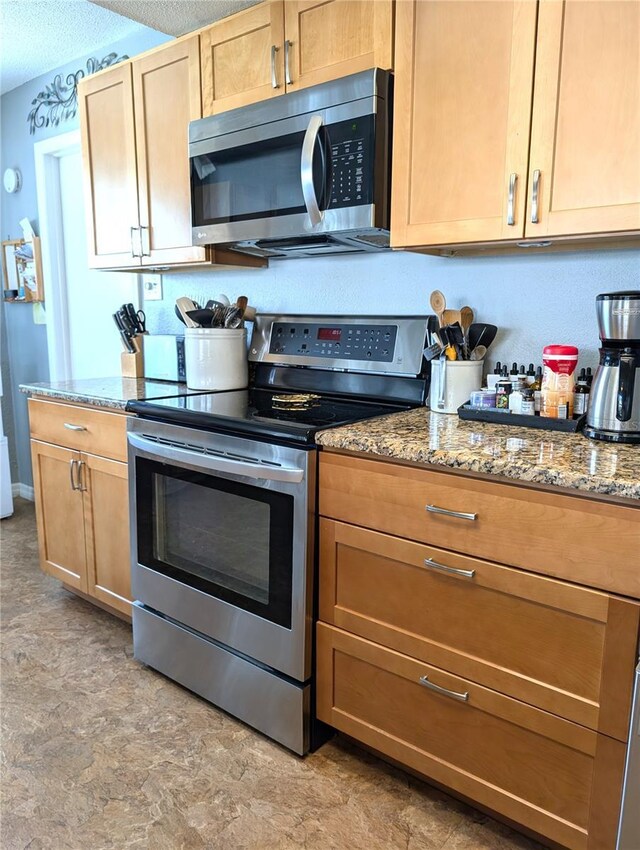 kitchen featuring stone countertops, a textured ceiling, and appliances with stainless steel finishes