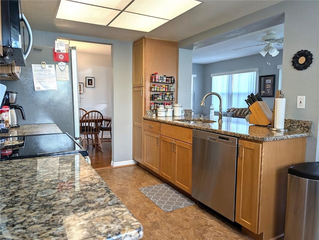 kitchen featuring stainless steel appliances, stone countertops, sink, and ceiling fan