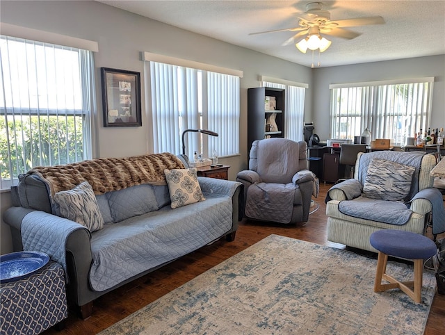 living room featuring dark wood-type flooring, a textured ceiling, and ceiling fan