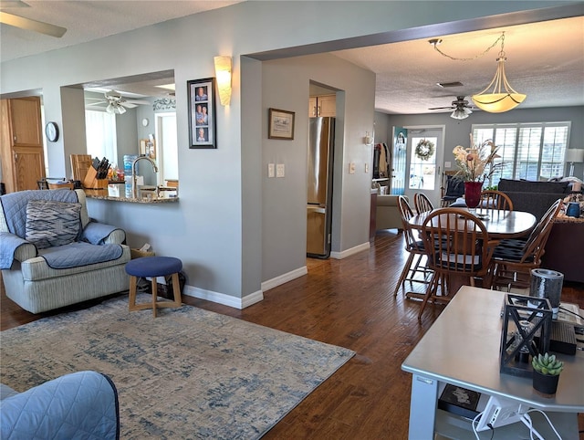 living room featuring ceiling fan, dark wood-type flooring, and a textured ceiling