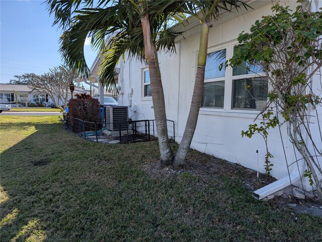 view of property exterior featuring central AC unit and a lawn