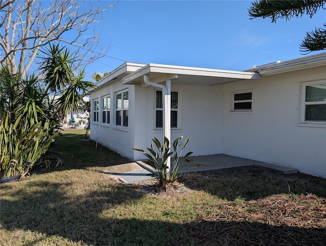 view of side of home with a patio and a lawn