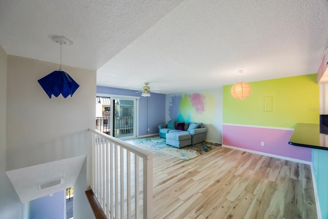 interior space with ceiling fan, a textured ceiling, and hardwood / wood-style flooring