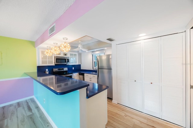 kitchen featuring kitchen peninsula, light wood-type flooring, white cabinetry, and stainless steel appliances