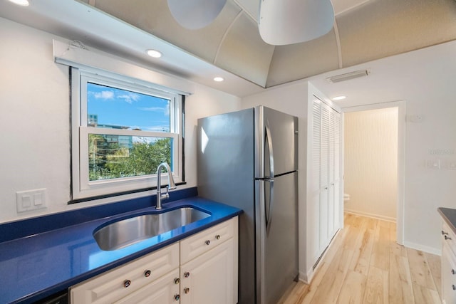 kitchen featuring stainless steel fridge, light hardwood / wood-style floors, white cabinetry, and sink