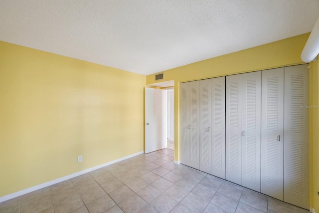 unfurnished bedroom with light tile patterned floors, a textured ceiling, and a closet