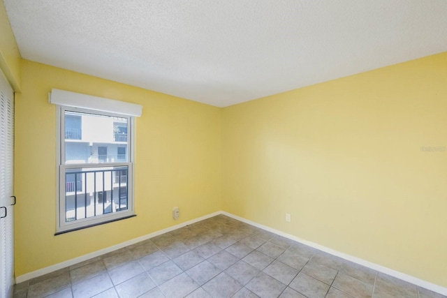 empty room featuring light tile patterned flooring and a textured ceiling