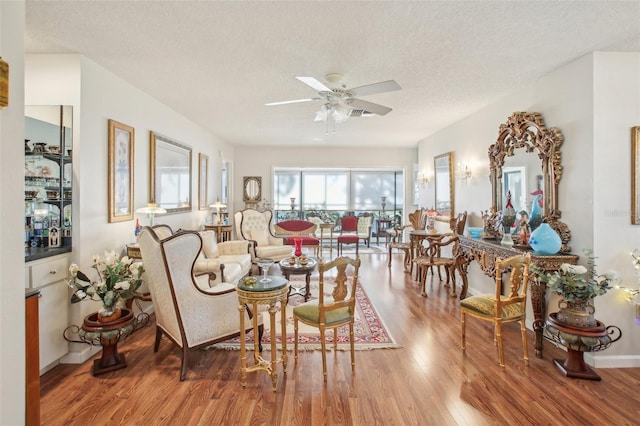 living room with a textured ceiling, light hardwood / wood-style flooring, and ceiling fan