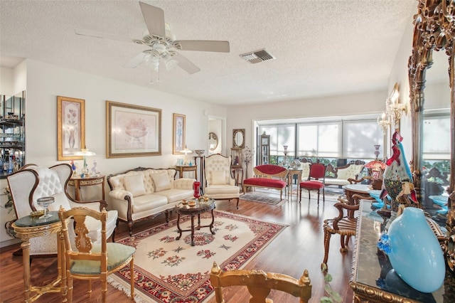 living room with wood-type flooring, a textured ceiling, and ceiling fan