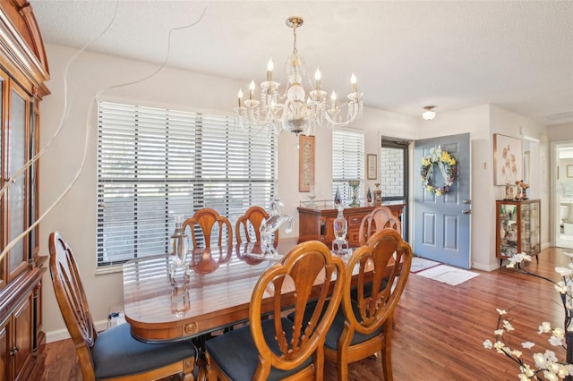 dining space featuring a textured ceiling, hardwood / wood-style flooring, and a notable chandelier