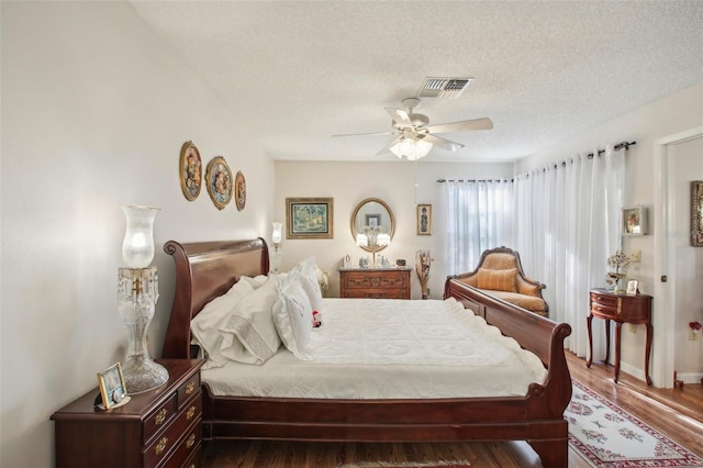 bedroom featuring a textured ceiling, ceiling fan, and dark hardwood / wood-style floors