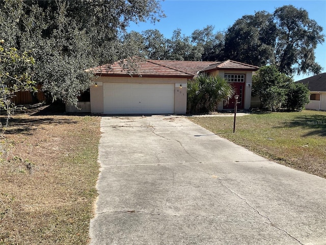 ranch-style house with a tile roof, concrete driveway, stucco siding, an attached garage, and a front yard