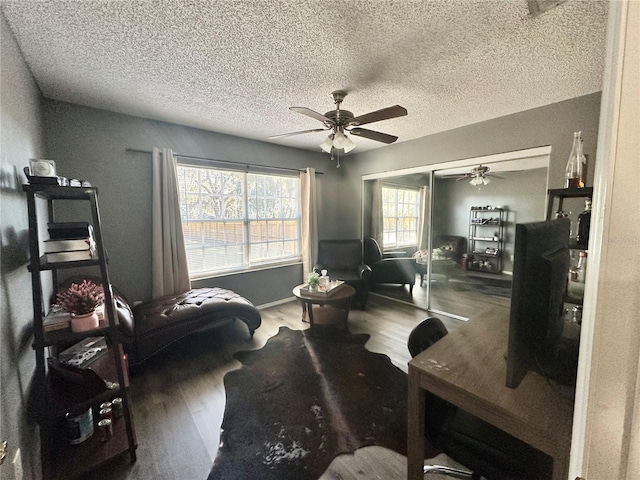 living area with hardwood / wood-style floors, ceiling fan, and a textured ceiling