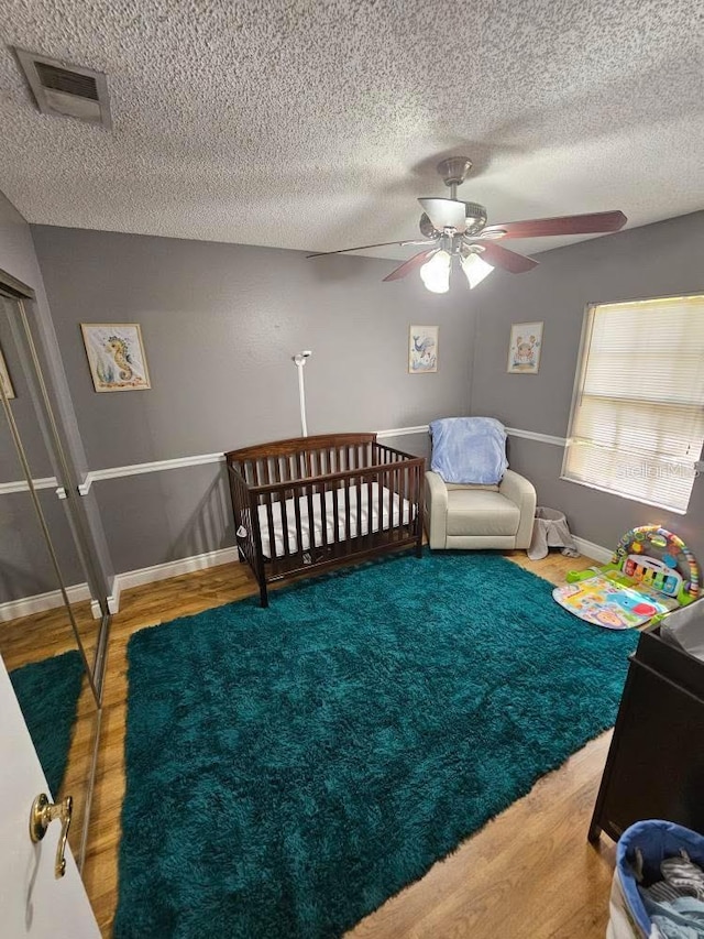 bedroom with baseboards, visible vents, a ceiling fan, and wood finished floors