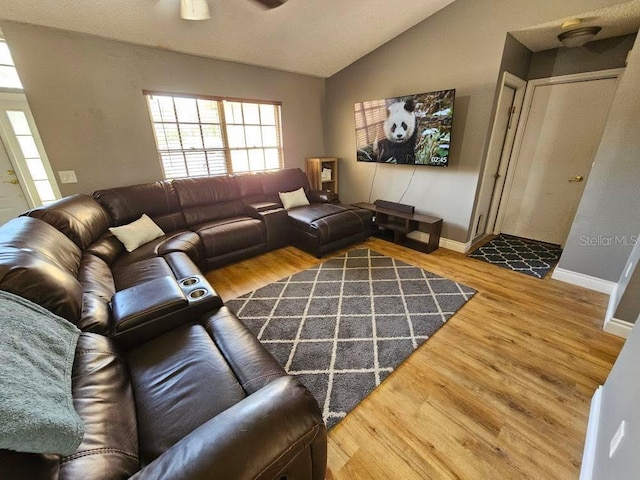 living room with baseboards, ceiling fan, wood finished floors, and vaulted ceiling