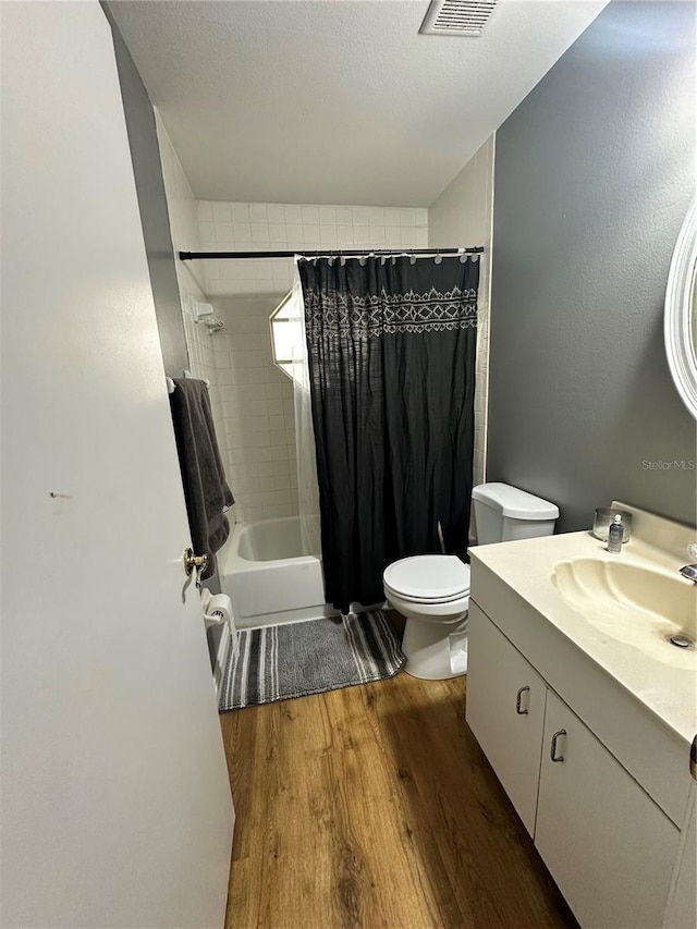 bathroom with a textured ceiling, visible vents, wood finished floors, toilet, and vanity