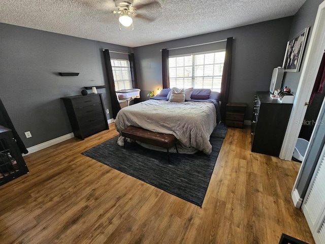bedroom with baseboards, a textured ceiling, wood finished floors, and a ceiling fan