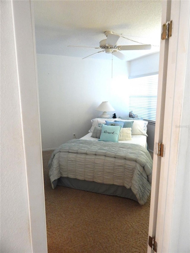 bedroom with ceiling fan, carpet floors, and a textured ceiling