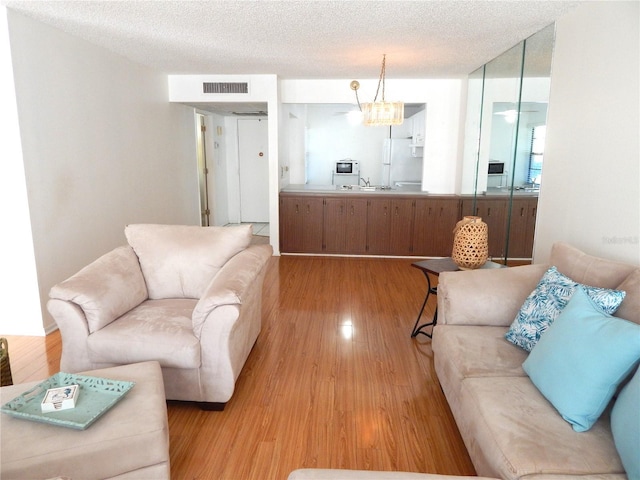 living room with sink, light hardwood / wood-style floors, and a textured ceiling