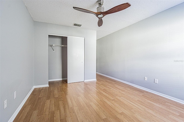 unfurnished bedroom featuring light hardwood / wood-style floors, a closet, ceiling fan, and a textured ceiling