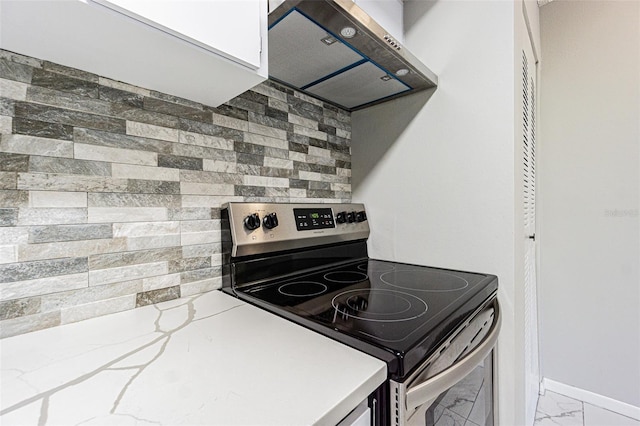 kitchen with wall chimney range hood, stainless steel electric stove, and light stone counters