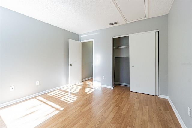 unfurnished bedroom with a textured ceiling, a closet, and light hardwood / wood-style flooring